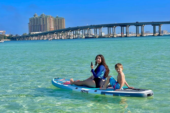 A girl and a little boy on top of a paddle board in Destin beach