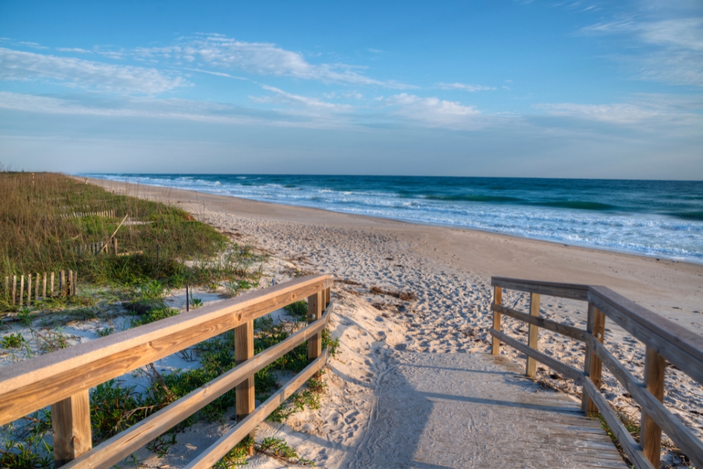 path and entrance to Canaveral National Seashore with white sands and blue ocean waters