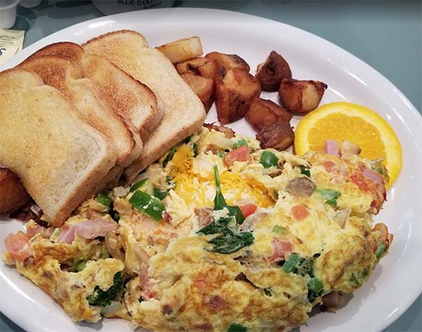 Blue Dolphin Cafe breakfast plate filled with delicious omelet a toasted sandwich and few meat 