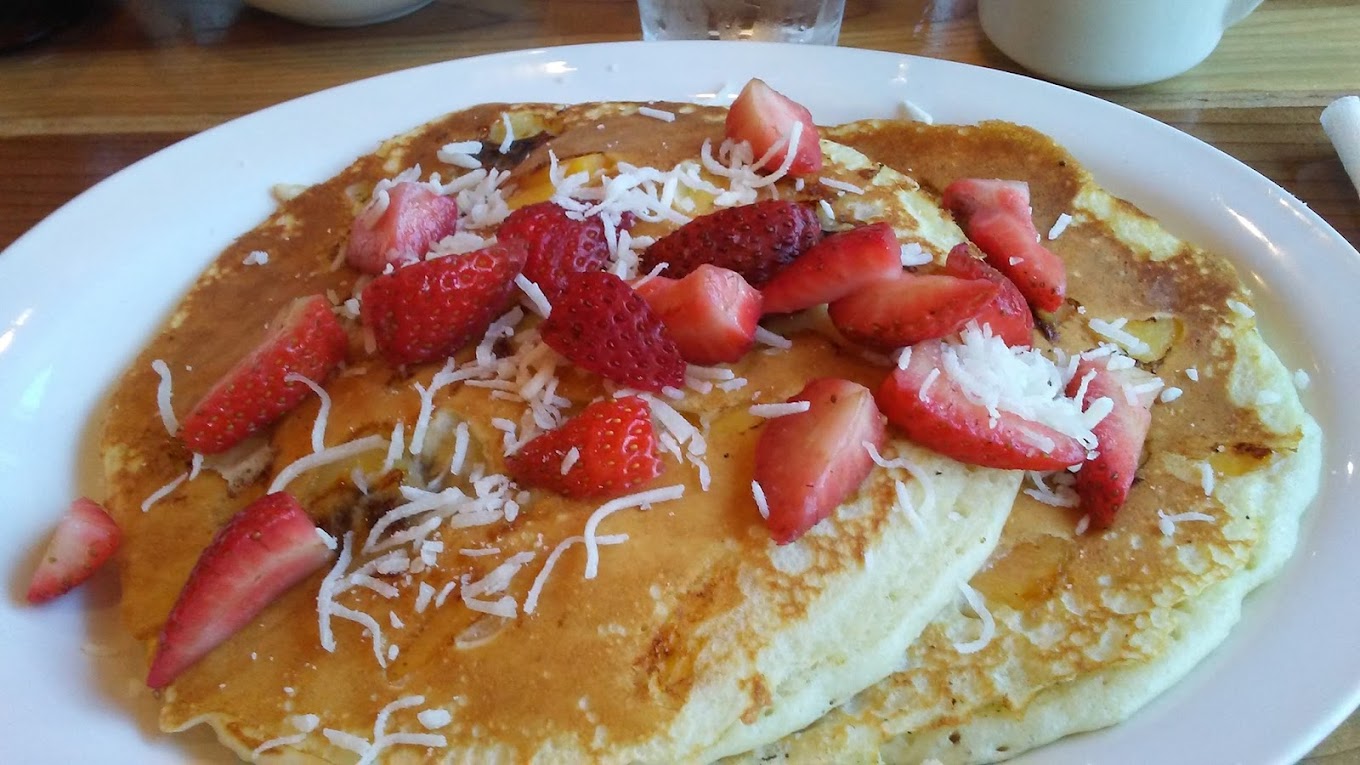 Original Word of Mouth fluffy pancakes topped with sliced strawberries and grated cheese
