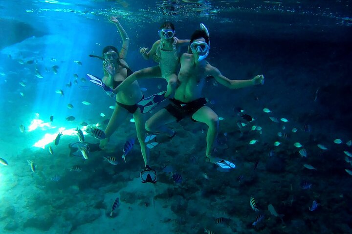 man and woman with a kid in the middle swimming underwater in the Bahamas